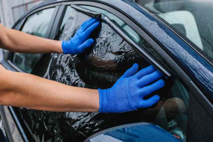 persona che mette pellicola su finestrino 